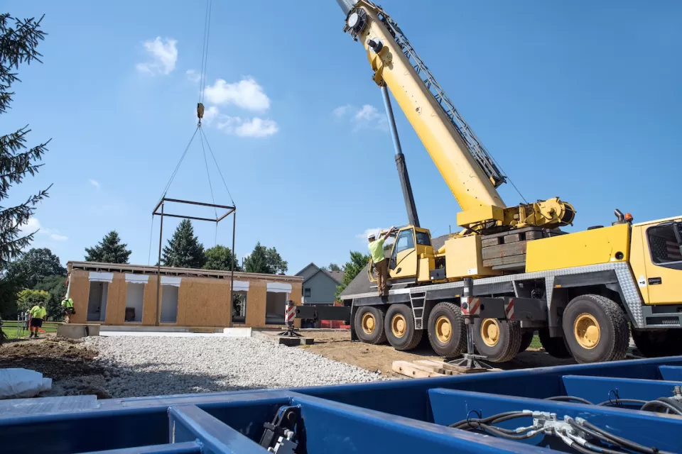 Modular home under construction with crane dropping in components.